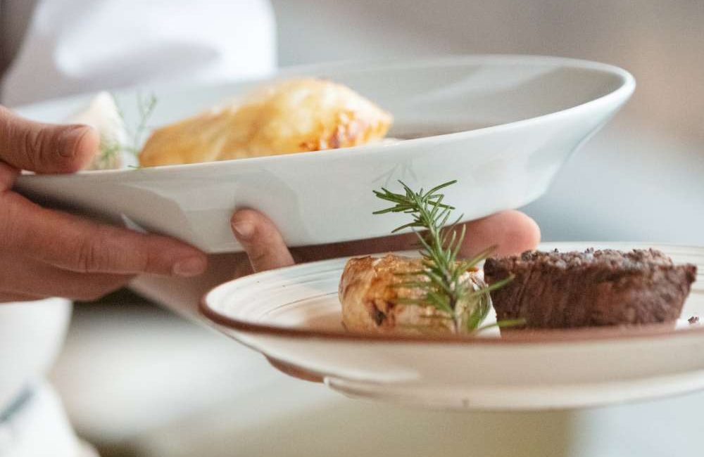 Ein Kellner serviert einem Gast im Restaurant Hotel zur Post in Kürthen sein essen.